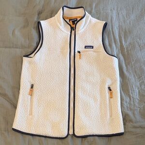 Patagonia cream/white fleece vest with navy trim and gold accents.